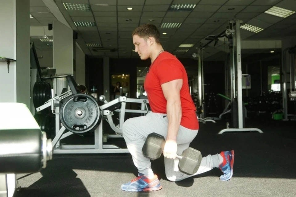 Мужчина в спортзале готовится поднять штангу