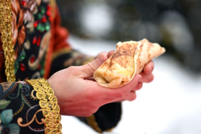 Креативное изображение земного шара, составленного из блинов, символизирующее распространение русской кухни и культуры по миру.