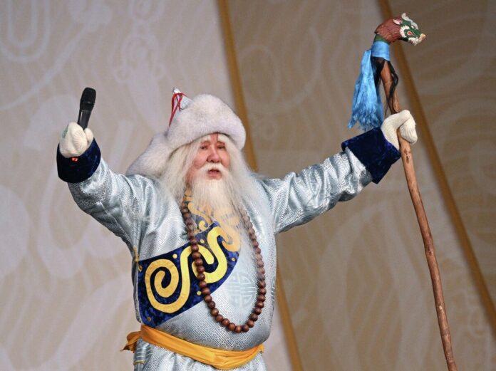 Бурятский Дед Мороз в окружении снежинок и традиционных бурятских узоров, улыбается.