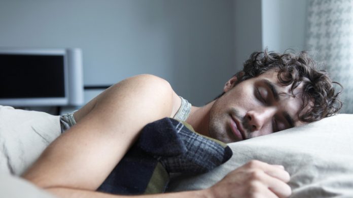 Мужчина сидит за столом, освещенный экраном монитора, с идеями для фильма, вдохновленными кошмарами, и с улыбкой предвкушает крепкий сон.