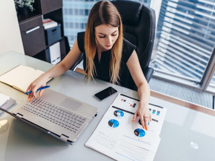 Человек держит в руке одну купюру, символизирующую начало инвестирования, на фоне размытого графика биржи и логотипа Уолл-стрит.