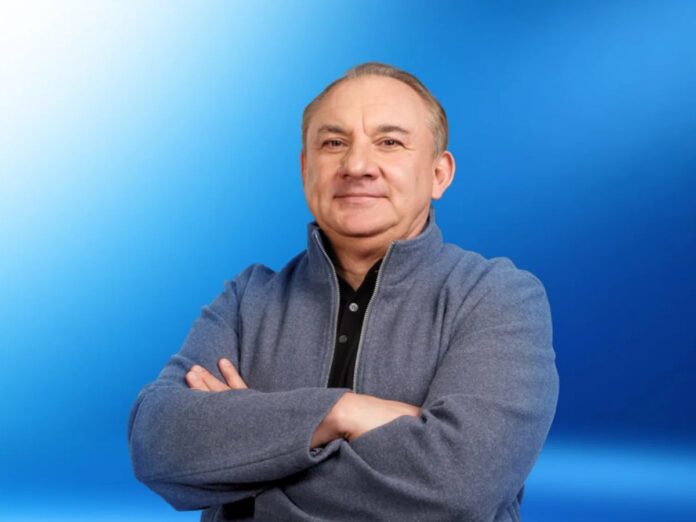 Николай Фоменко стоит рядом с автомобилем, улыбаясь.