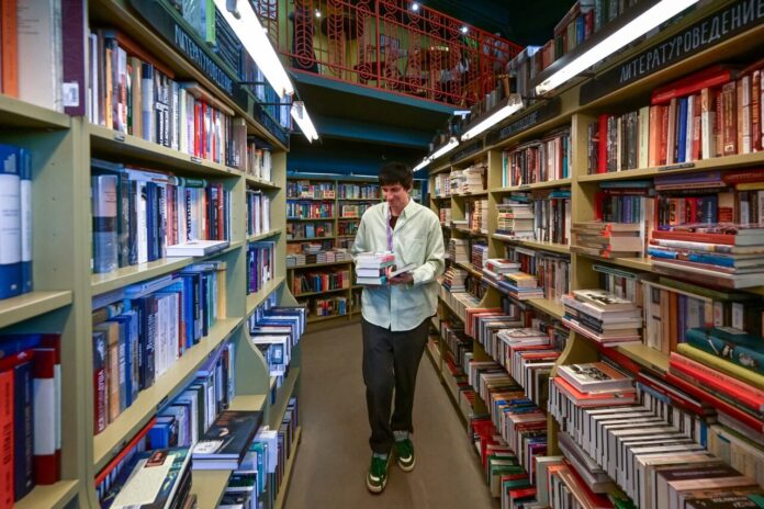 Обложка книги с изображением символики, намекающей на общение с Люцифером, на фоне множества книг, купленных россиянами.