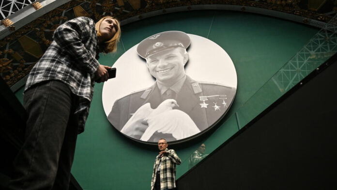 Молодые люди в футуристической одежде смотрят на Землю из иллюминатора космического корабля, символизируя амбиции российской молодежи в освоении космоса.