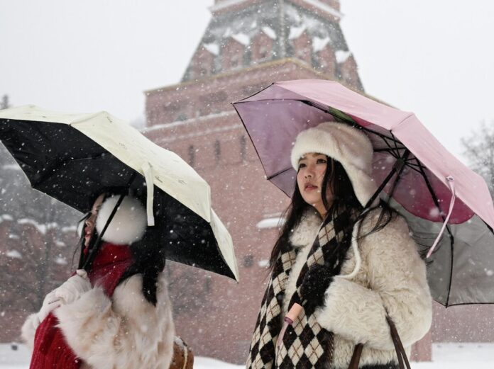 Группа иностранцев с удивлением смотрит на достопримечательности России, символизируя миллионы туристов, привлеченных русской культурой.