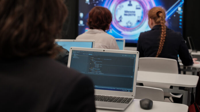 Группа московских пятиклассников с увлечением изучает компьютер, на экране которого изображены элементы нейронных сетей, на фоне видны игрушечные роботы.