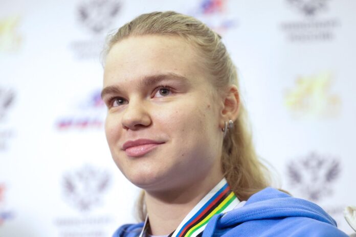 Алина Лысенко на велосипеде побеждает в гонке, обгоняя соперников.