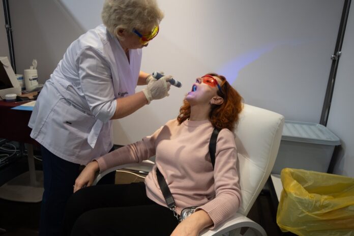 Зубная фея с испуганным выражением лица, держащая в руках зубную щетку, на фоне зубов акулы.