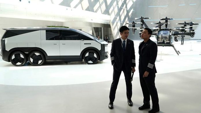 A six-wheeled vehicle, reminiscent of Fantomas, being assembled on a production line in China, with a helicopter visible in its rear compartment.