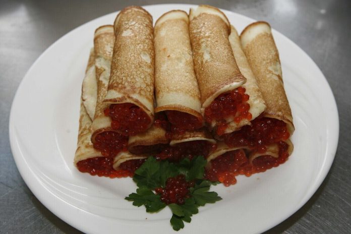 Яркие, румяные блины, символизирующие солнце, на тарелке