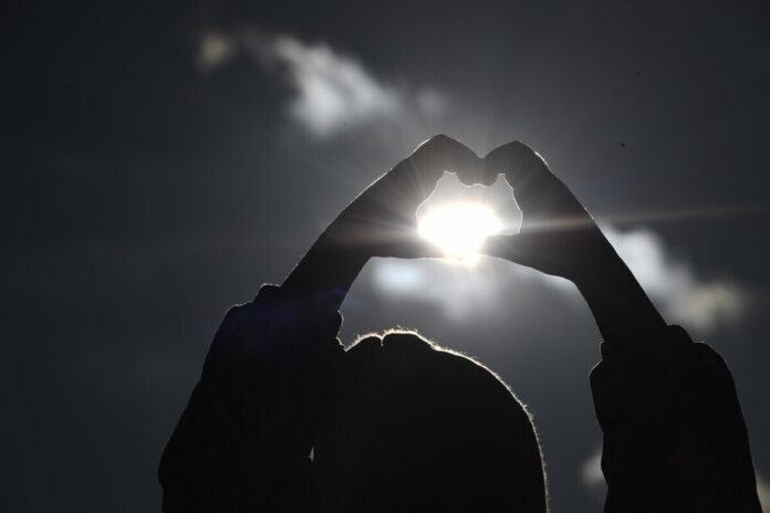 Иллюстрация, изображающая пингвинов, наблюдающих за Солнцем, которое выглядит как пончик, и Луной, уменьшающейся в размере.