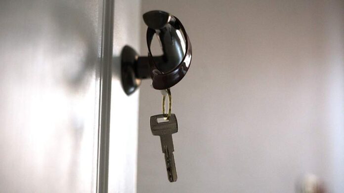 Молодая пара студентов с ключами от квартиры на фоне дома