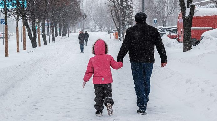 Счастливая семья с тремя детьми, мужчина получает чек на 2 миллиона рублей, символизирующий государственную поддержку за рождение третьего ребенка.