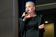 Лариса Долина в театральном костюме, изображающая сцену с студенческим билетом